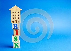 Wooden blocks with the word Risk and a miniature house. Real estate investment risk. Risky investments. Loss of property for non-