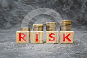 Wooden blocks with the word risk and money coin stack on dark background. Financial debt decrease concept