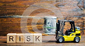 Wooden blocks with the word Risk, money and a forklift. Financial and commercial risk concept. Investing in a business. Risks