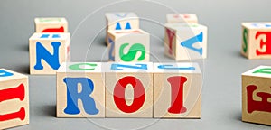 Wooden blocks with the word ROI. Ratio between the net profit and cost of investment resulting from an investment of resources.
