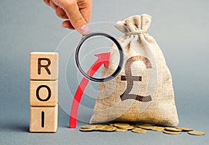 Wooden blocks with the word ROI and the up arrow with the money bag. High level of business profitability. Return on investment,