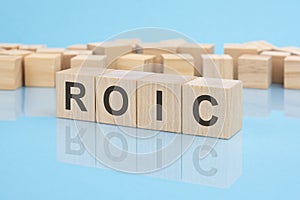 wooden blocks with the word ROIC, blue background