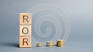 Wooden blocks with the word ROR and coins. High level of business profitability. Return on investment, invested capital, rate.