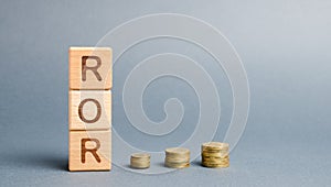 Wooden blocks with the word ROR and coins. High level of business profitability. Return on investment, invested capital, rate. photo