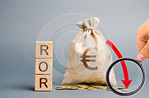 Wooden blocks with the word ROR, money bag and down arrow. Financial ratio illustrating the level of business loss. Return on