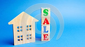 Wooden blocks with the word Sale and wooden miniature house. The concept of the sell of real estate, apartments and residential