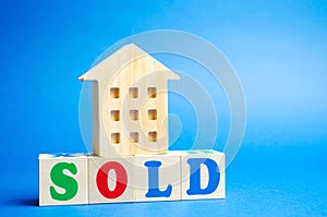 Wooden blocks with the word Sold and wooden miniature house. The concept of the sell of real estate, apartments and residential