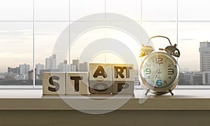 Wooden blocks with the word START-STOP and clock on table with panoramic city skyline background in the morning. Start, Start up,