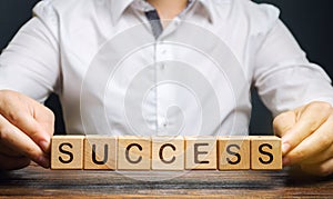 Wooden blocks with the word Success and businessman. Successful business concept. Achieving the goal, overcoming difficulties. The