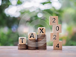 Wooden blocks with the word TAX 2024 on stack of coins. The concept of prepare to pay tax in new year 2024