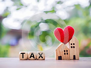 Wooden blocks with the word TAX and miniature house. The concept of paying tax for house and property. Property taxes