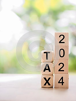 Wooden blocks with the word TAX and number 2024. The concept of prepare to pay tax in new year 2024