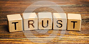 Wooden blocks with the word Trust. Trust relationships between business partners, friends, relatives. Respect and authority.