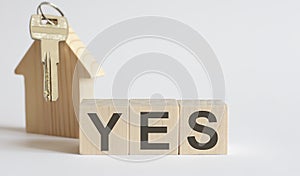 Wooden blocks with the word YES , house. The concept of the high cost of rent for an apartment or home