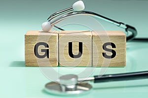 Wooden blocks with the words GUS, urogenital system, medical stethoscope, health concept, regular examinations