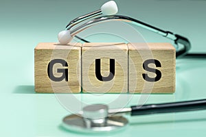 Wooden blocks with the words GUS, urogenital system, medical stethoscope, health concept, regular examinations photo