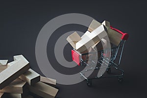 Wooden blocks near and in shopping cart on brown background. Template with shopping cart, home, blocks, copy space. Saving money