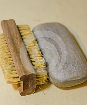 wooden boar bristle brush and smooth grey soap bar on warm beige surface photo