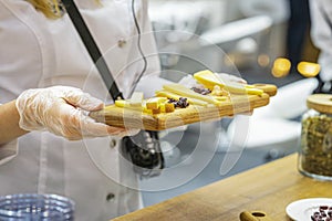 Wooden board with assorted cheeses in hands of promoter girl