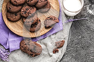 Wooden board with chocolate cookies and glass of milk on table