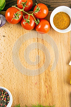 Wooden board with clear space. Around tomato and dill, olive oil, spice, peper, avocado, green onion, spinac and garlic. Top views