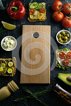 Wooden board with clear space. Around tomato, souce, olives, lemon, olive oil with spice and sandwiches