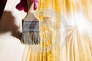 Wooden board is covered with wood stain close up