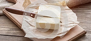 Wooden board with cut block of butter.Knife on a rustic table and butter