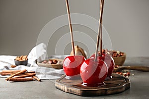 Wooden board with delicious candy apples on table