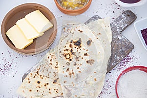 Wooden board dusted with flour with grilled pita, taco, shawurma lying on table with cheese. photo