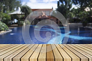 Wooden board empty table against of blurred swimming pool background. Perspective brown wood over swimming pool.