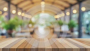 Wooden board on empty table in front of blurred background, perspective brown wood table over blur forest for mockup or product