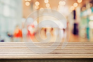 Wooden board empty table top with blur in shopping mall background.