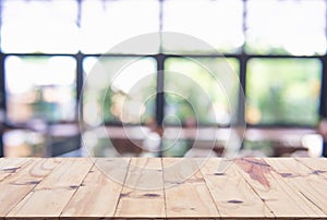 Wooden board empty table top on of blurred background. Perspective brown wood table over blur in coffee shop background - can be u