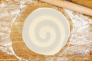 Wooden board with flour, dough and rolling pin