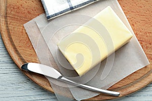Wooden board with fresh butter and knife on table
