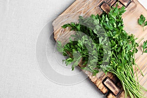 Wooden board with fresh green parsley and space for text on light fabric