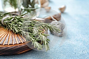 Wooden board with fresh rosemary on table, closeup
