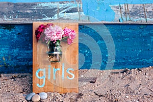 Wooden board with inscription girls and a vase attached to the board with peonies.