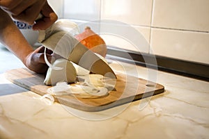 Wooden board and knife cutting onion in the kitchen