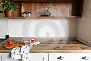 Wooden board with knife, tomatoes on modern kitchen countertop a