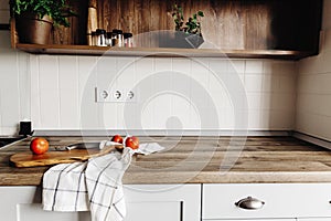 Wooden board with knife, tomatoes on modern kitchen countertop a