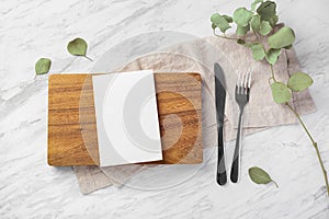 Wooden board and menu card mockup with fork and knife on marble kitchen table