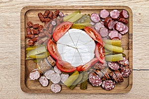 Wooden board with pieces of meat, blue cheese and vegetables, on the kitchen counter, top view.