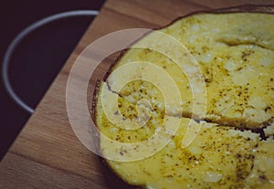 On a wooden Board in a plate is a fresh fried omelet made of eggs and milk