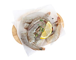 Wooden board with raw shrimps, lemon and thyme on white, top view