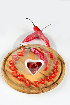 Wooden board with red pepper cut into slices hot sauce with copy space white background