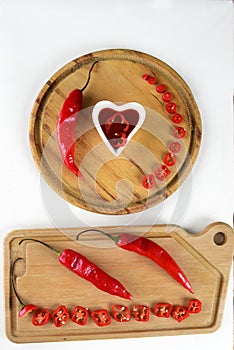 Wooden board with red pepper cut into slices hot sauce with copy space white background