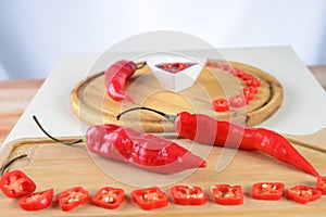 Wooden board with red pepper cut into slices hot sauce with copy space white background