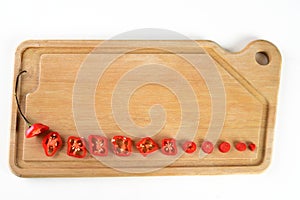 Wooden board with red pepper cut into slices hot sauce with copy space white background